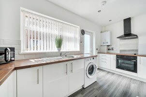 Une cuisine moderne équipée d’un lave-linge, d’une cuisinière et d’un four à micro-ondes.