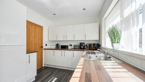 A modern kitchen with white cabinets, a wooden countertop, a sink, and a window with natural light. - 3-beds, Sleeps 6 Walking Distance to Castle & Town (Abergele)