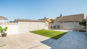 A patio with a lawn, a table and chairs, and a stone wall. - 3-beds, Sleeps 6 Walking Distance to Castle & Town (Abergele)