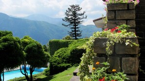 A landscaped garden with a stone wall, flower boxes, and a view of mountains.