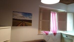 Een kamer met een raam, een schilderij aan de muur en een houten plafond.