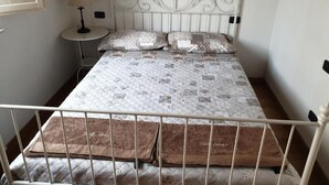 Un letto con una trapunta decorata, due cuscini e un comodino con una lampada.