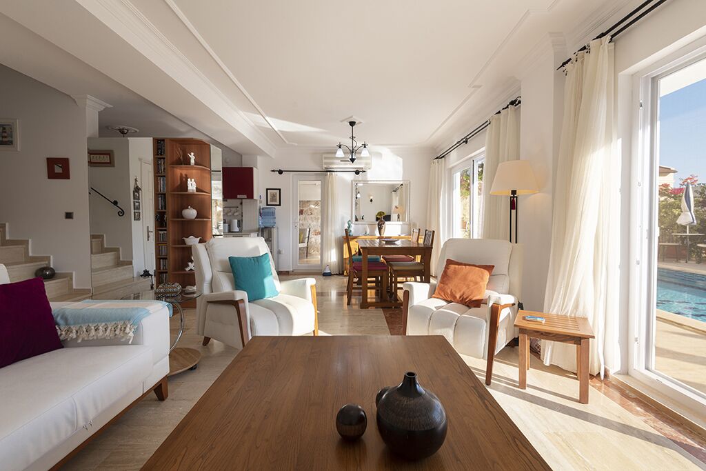 Un salon spacieux avec une table basse en bois, des canapés blancs et un coin repas comprenant une table et des chaises.