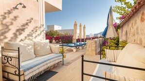 Une terrasse sur le toit avec une piscine, des sièges extérieurs et des parasols.