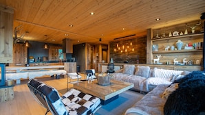 A spacious living area with a wooden ceiling, a sofa, a coffee table, and a fireplace. - Chalet Angel - magnifique vue sur le lac (Les Angles)