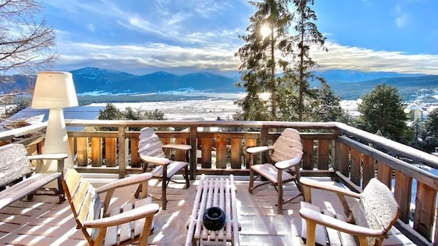 A wooden deck with outdoor seating and a view of a snowy landscape and mountains. - Chalet Angel - magnifique vue sur le lac (Les Angles)