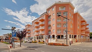 Un hôtel à plusieurs étages doté de balcons, d’un panneau indiquant un parking et surplombant un ciel dégagé.