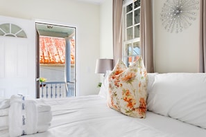 Une chambre d’hôtel avec un lit, une fenêtre avec des rideaux, un élément décoratif mural et un balcon avec une balustrade.