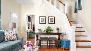A living room with a sofa, coffee table, and a staircase. - Where Tranquility Blooms | Blossoms on Cannon (Charleston)