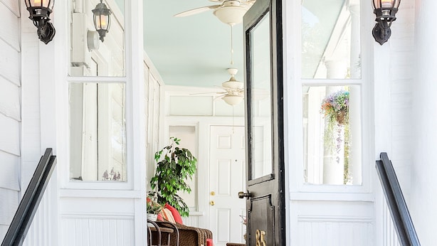 A staircase leading to a room with a black door, white walls, and a hanging plant. - Where Tranquility Blooms | Blossoms on Cannon (Charleston)