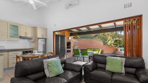 A modern kitchen with a built-in stove, a dining area with a table and chairs, and a living area with two leather sofas and a coffee table. - San Lameer Villa Rentals 2019 (Southbroom)