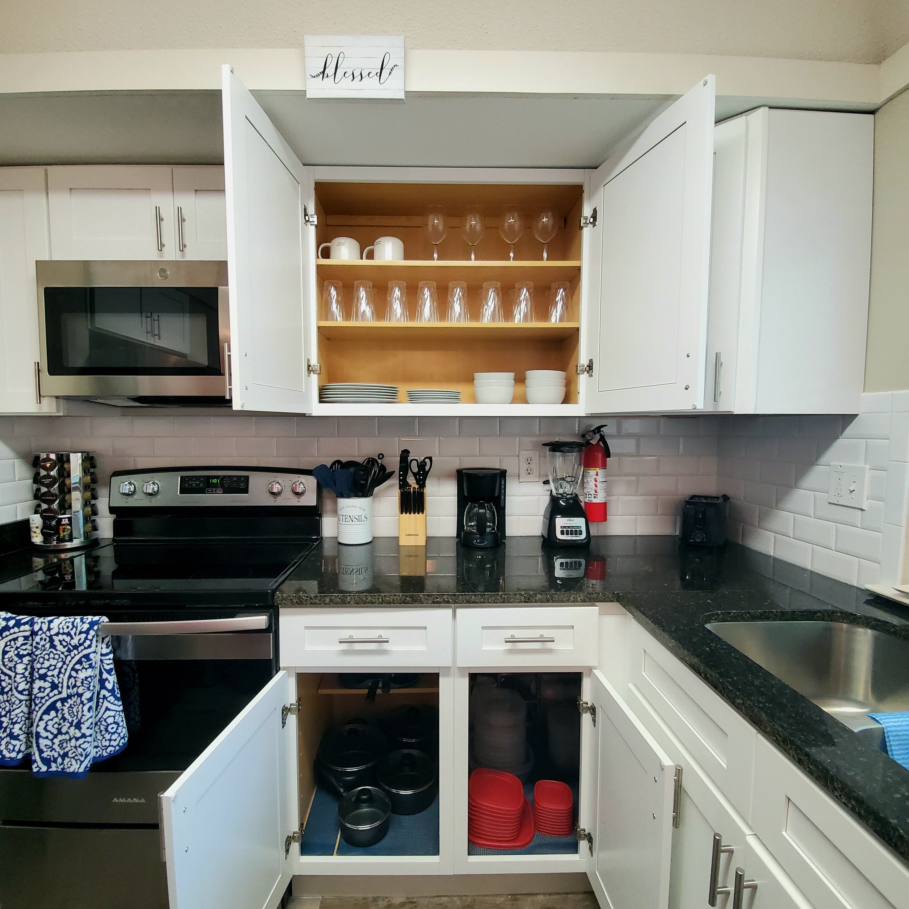 A kitchen with white cabinets, a microwave, a stove, and a sink.