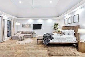 A modern bedroom with a bed, a sofa, a small table, and a plant.