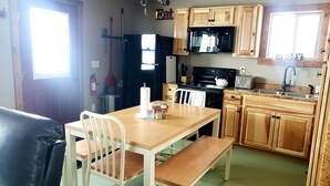 A compact kitchen with wooden cabinets, a microwave, a toaster, and a sink. - Shedhorn Cabin #2 of 3 - 1 BEDR & Full RV Hookups (White Sulphur Springs)