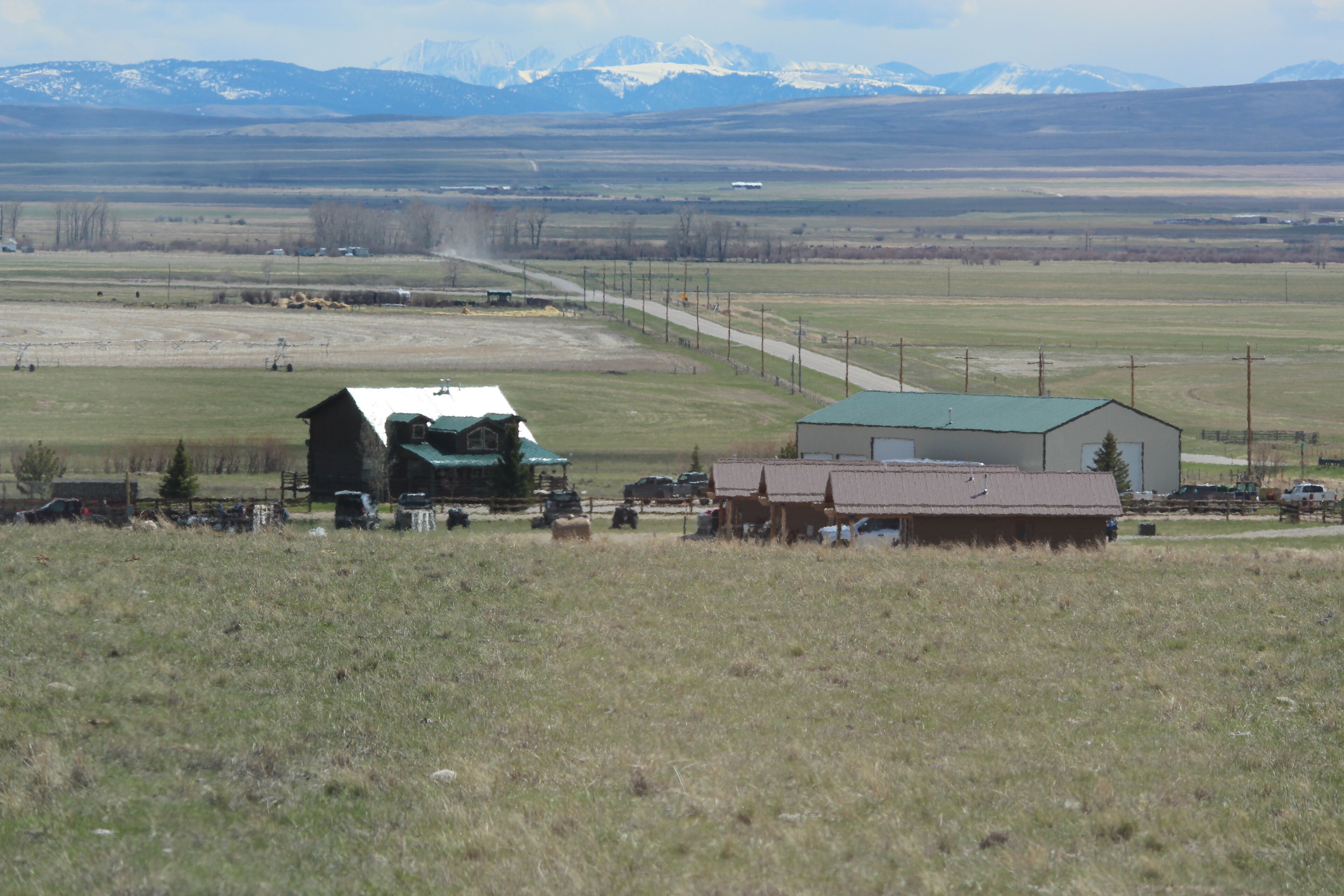 Un paysage rural avec une grange, un petit bâtiment et une route.