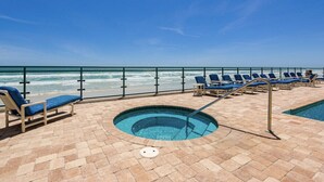 A pool area with lounge chairs and a hot tub, overlooking the ocean. - Oceanfront Penthouse ~ Professionally Designed (Daytona Beach Shore)