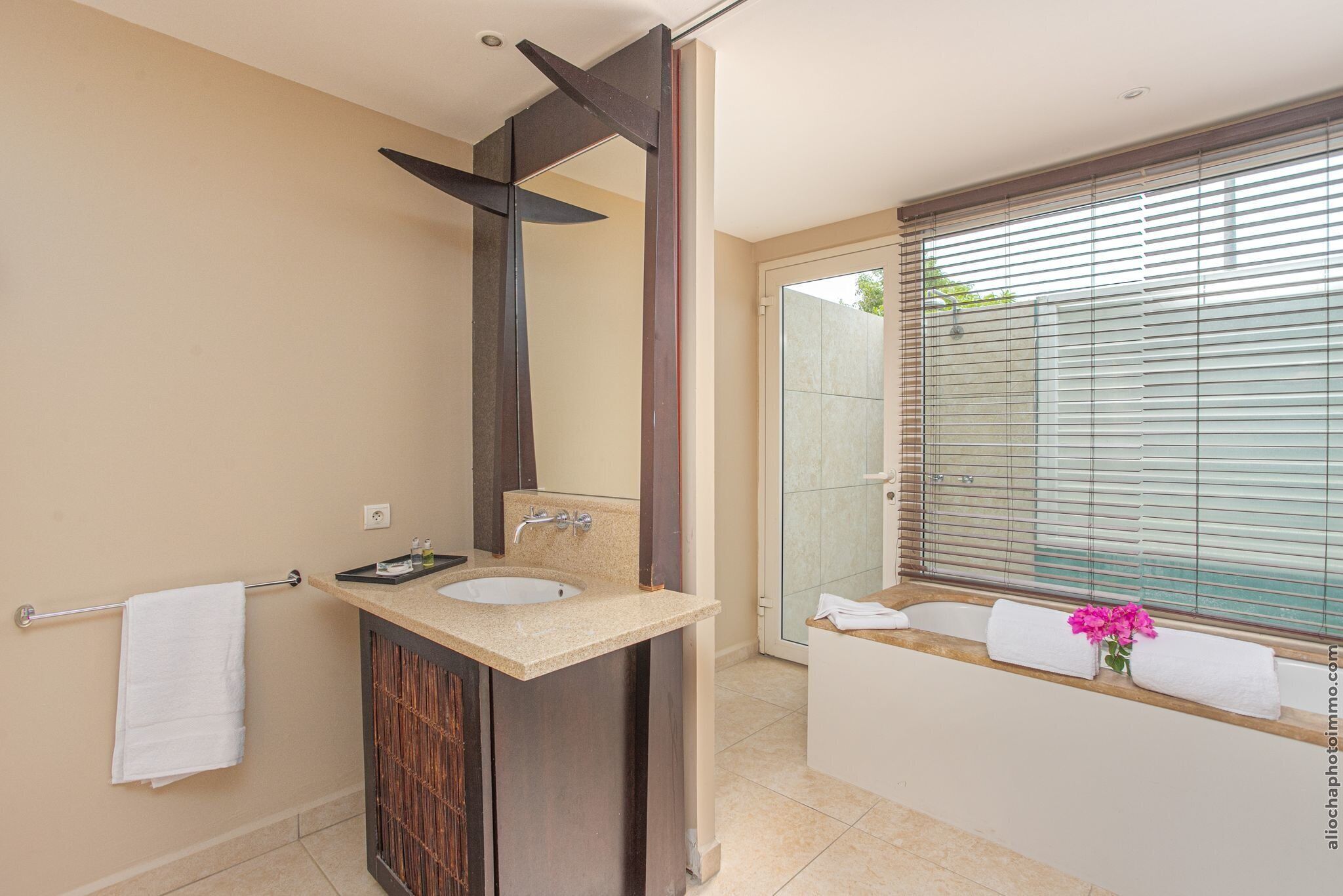 A modern bathroom with a large mirror, a sink, and a bathtub.