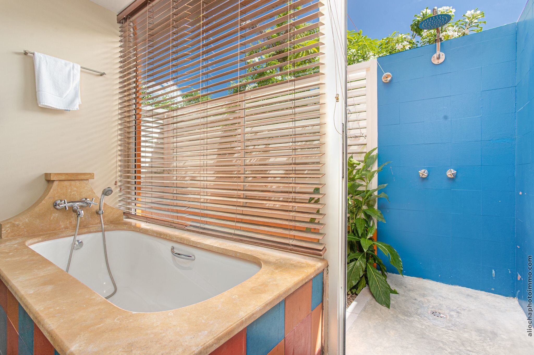 A bathroom with a bathtub, a shower, and a blue wall.