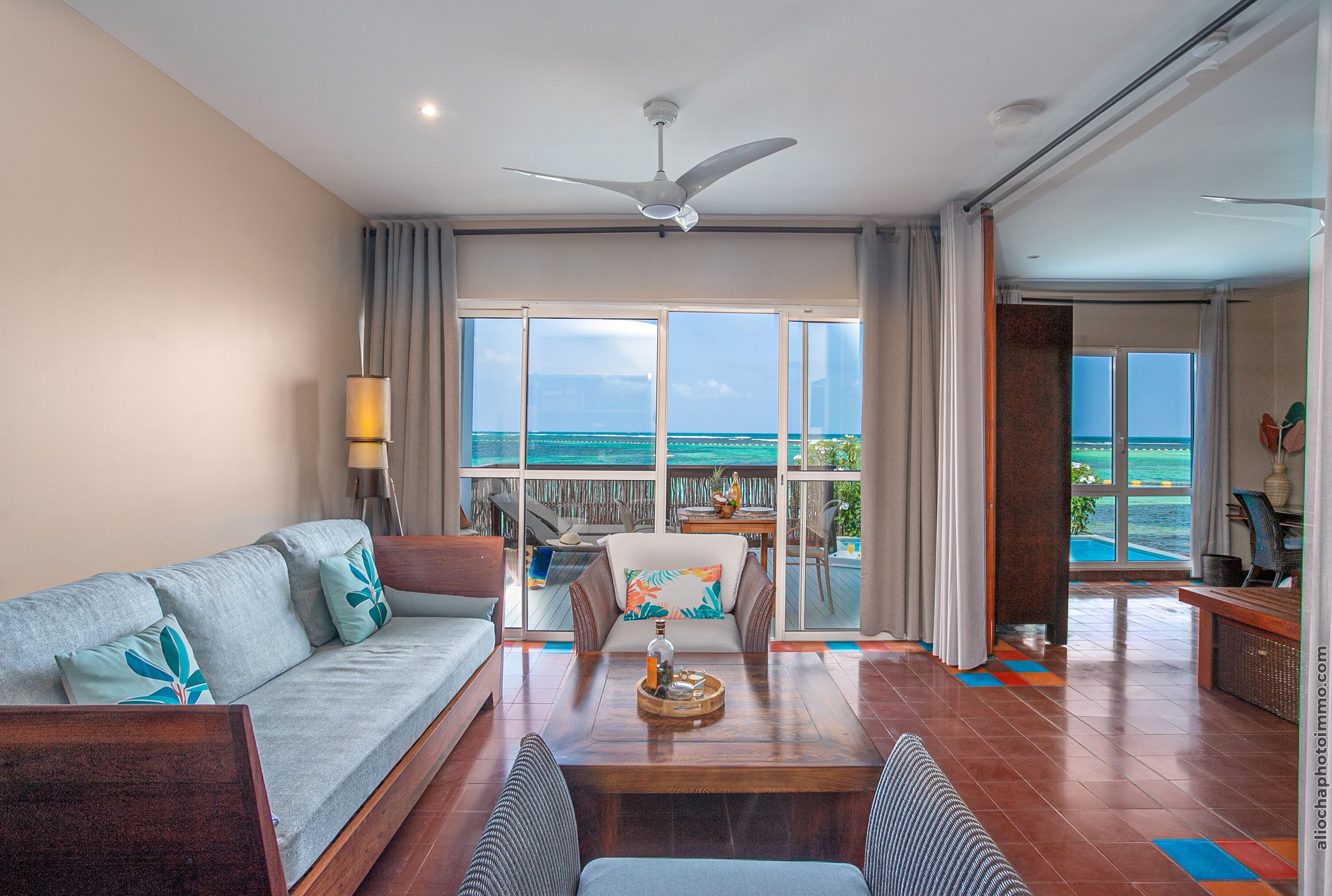 A spacious living room with a sofa, coffee table, and a view of the ocean through large windows.
