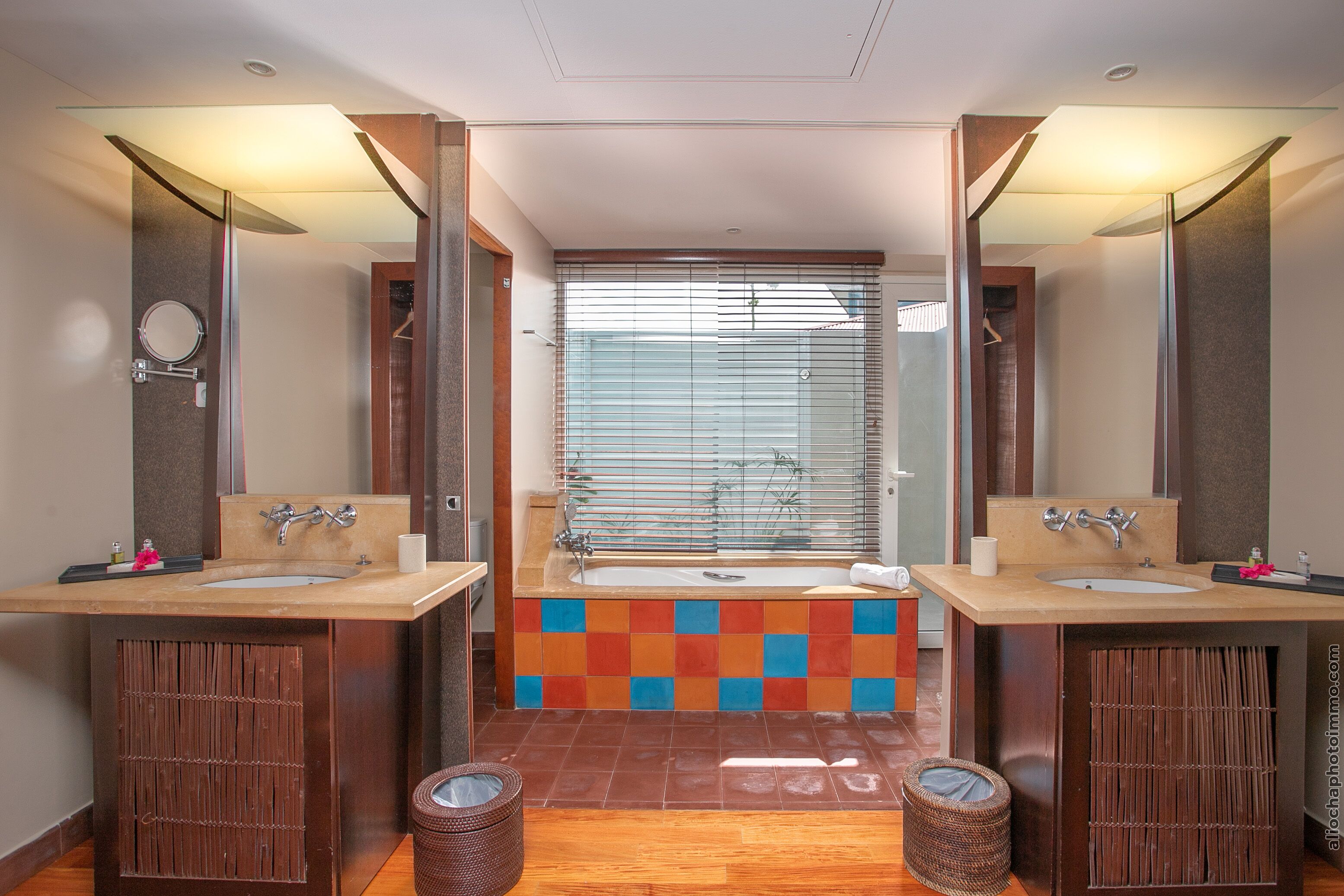 Une salle de bain moderne avec deux lavabos, une grande baignoire et un miroir au-dessus de chaque lavabo.