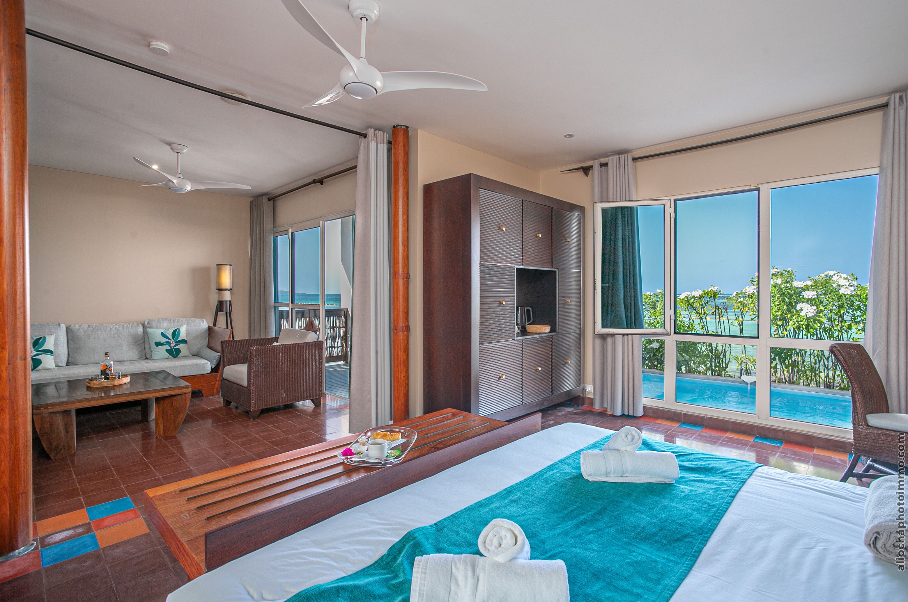 Una camera d'albergo con un letto grande, un divano, un tavolo da pranzo e vista sull'oceano.