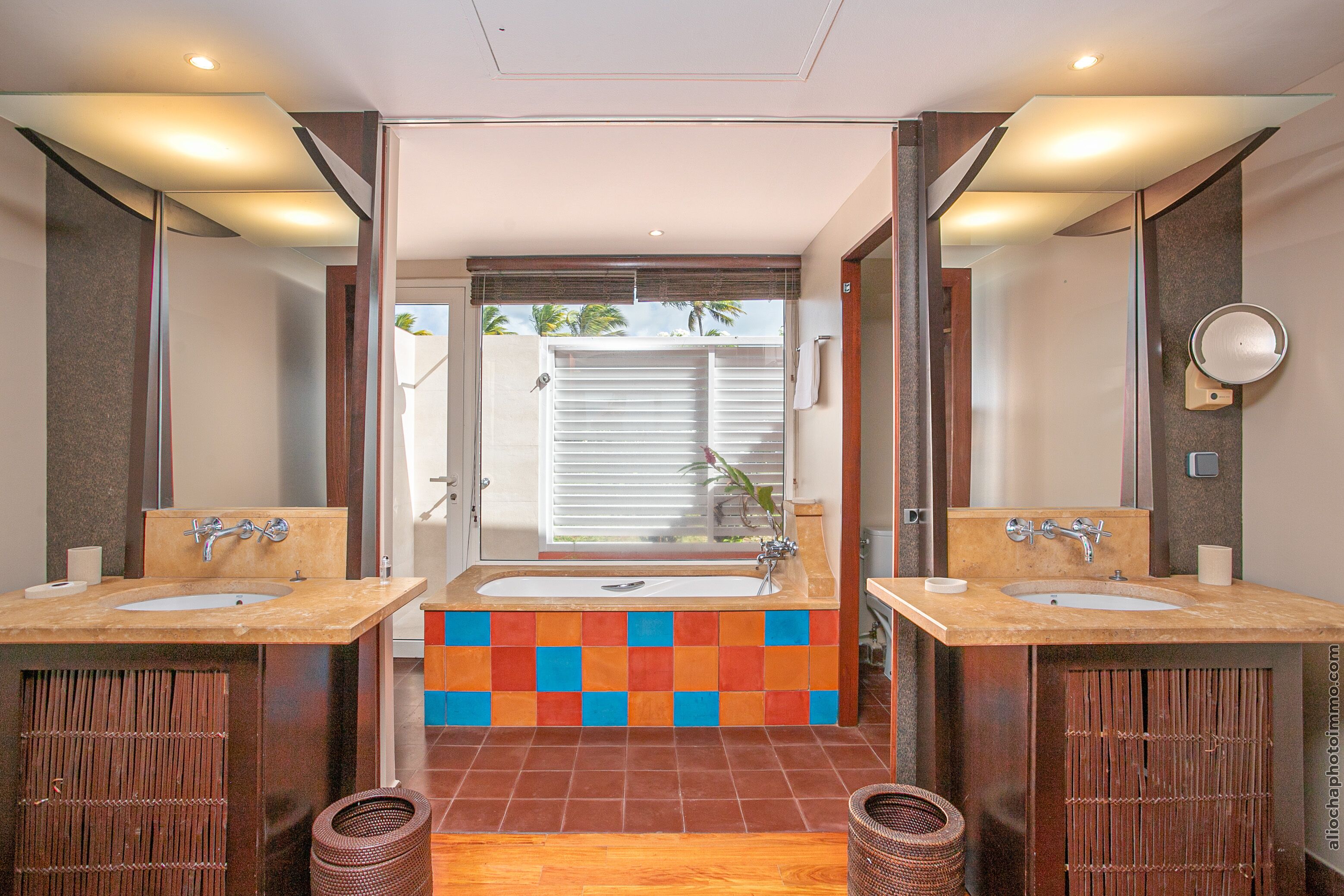 A bathroom with two sinks, a large bathtub, and a colorful tile backsplash.