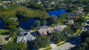 Vista aérea de una zona residencial con casas, un estanque e instalación de paneles solares.