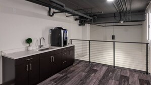A modern kitchen with dark cabinetry, a stainless steel sink, and a coffee machine. - Modern Luxury 1BR Apt with Rooftop, Gym, and Parking (Milwaukee)