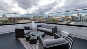 A modern rooftop terrace with a city view, featuring a sectional sofa, two armchairs, and a coffee table. - Modern Luxury 1BR Apt with Rooftop, Gym, and Parking (Milwaukee)