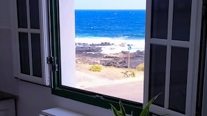 Ein Fenster mit Blick auf das Meer und eine felsige Küste.