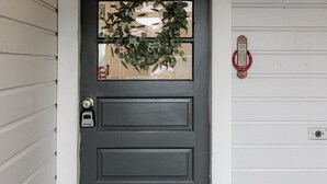 A dark gray door with a welcome sign above it.