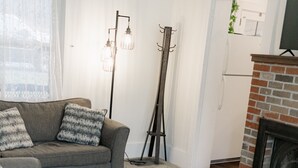 A living room with a sofa, a coffee table, a fireplace, and a ladder leaning against the wall.