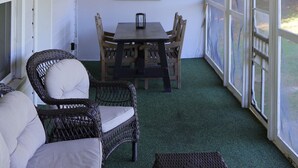 A covered porch with wicker furniture, ceiling fans, and string lights.