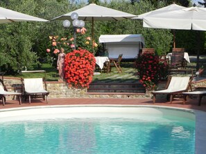 Ein Poolbereich mit Liegestühlen, Sonnenschirmen und einer Statue.