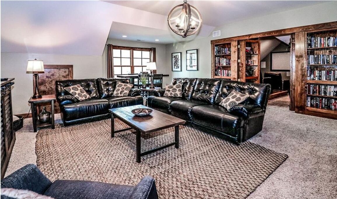 A living room with a leather sofa set, a coffee table, and a bookshelf.