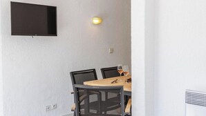 A dining area with a round table, four chairs, and a flat-screen TV mounted on the wall. - Family 40 - Cap Sud Vacances, La Garde-Freinet (La Garde-Freinet)