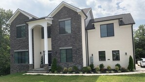 A two-story house with a stone facade, large windows, and a well-maintained lawn. - Modern newly private basement apartment  (Alexandria)