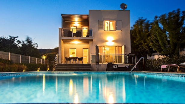A modern two-story house with a swimming pool in front.