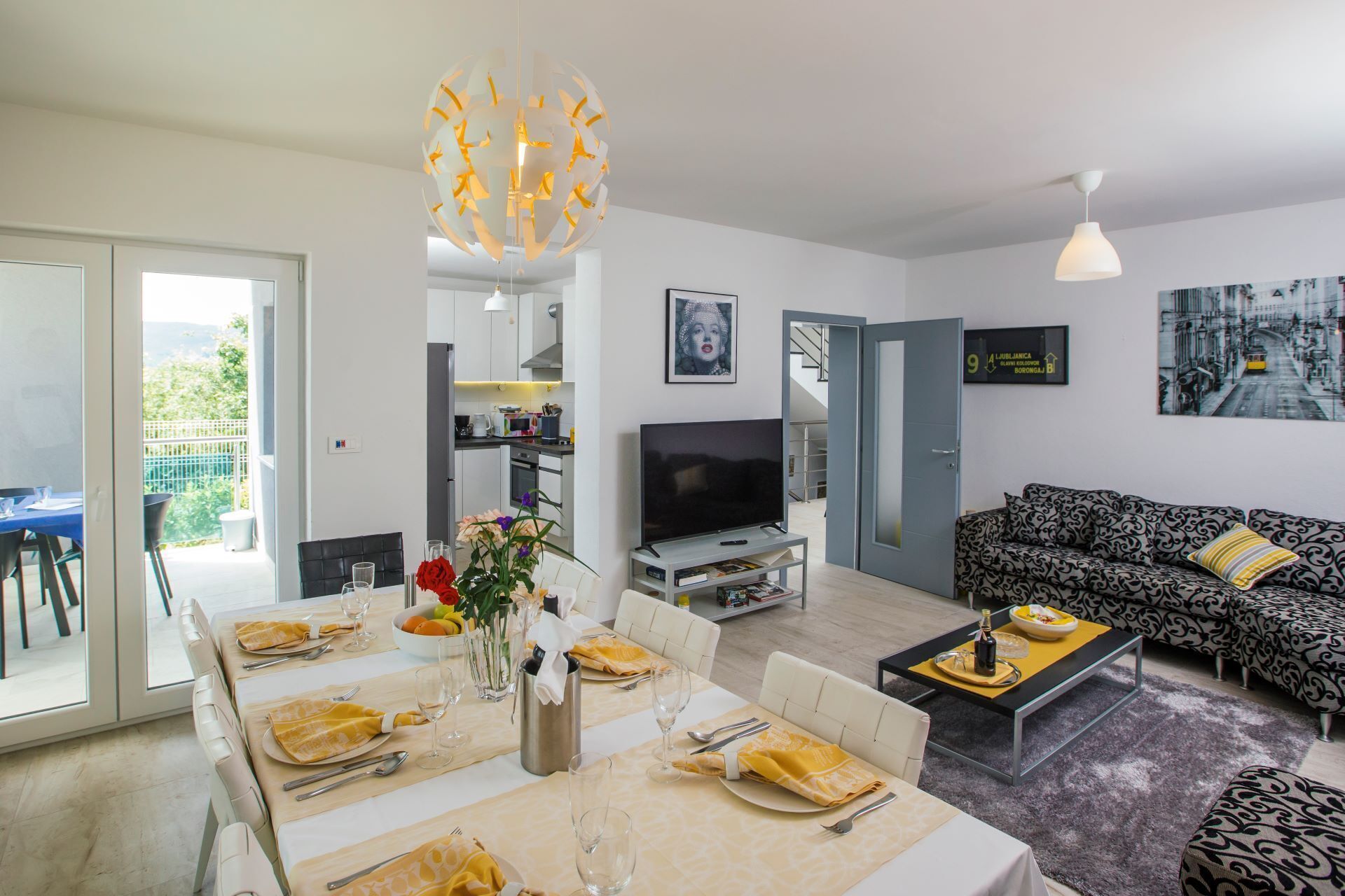 Una sala de estar moderna con comedor, televisor y sofá.