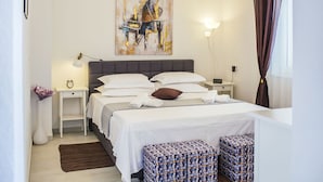 A modern bedroom with a large bed, bedside tables, a lamp, and a painting on the wall.