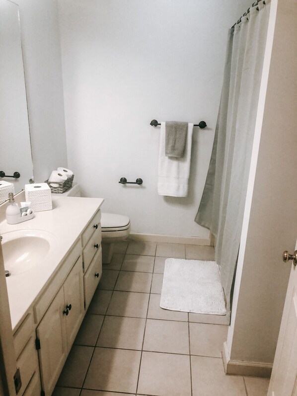 A bathroom with a sink, toilet, and shower area.