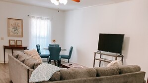 A living room with a sectional sofa, a ceiling fan, a dining table with chairs, and a TV on a stand. - 2 BR / 2 BA UNIT! WALKING DISTANCE FROM SQUARE AND CAMPUS!! (Oxford)