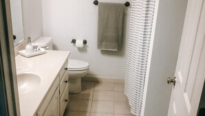 A bathroom with a toilet, sink, and shower curtain. - 2 BR / 2 BA UNIT! WALKING DISTANCE FROM SQUARE AND CAMPUS!! (Oxford)