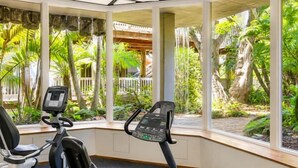 An indoor exercise area with stationary bikes and a view of a tropical garden. - Garden-View Condo at North Coast Village | G5 (Oceanside)