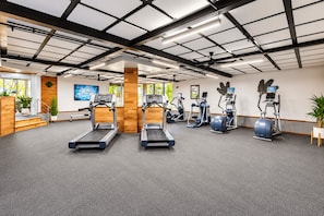 Un gimnasio con cintas de correr, elípticas y una bicicleta estática.