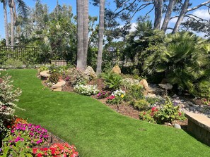 A landscaped garden with a variety of plants and a well-maintained lawn. - Garden Cottage G5 + Patio | North Coast Village (Oceanside)