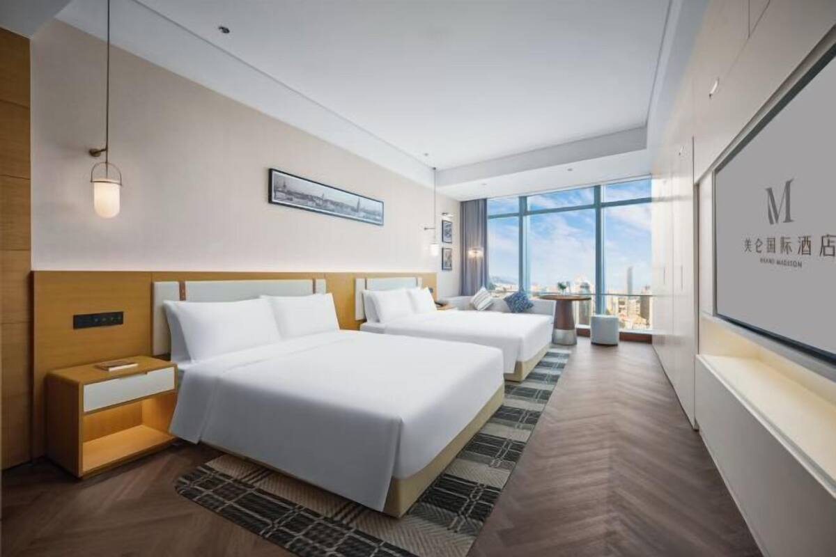 A hotel room with two beds, a large window, and a view of the city.
