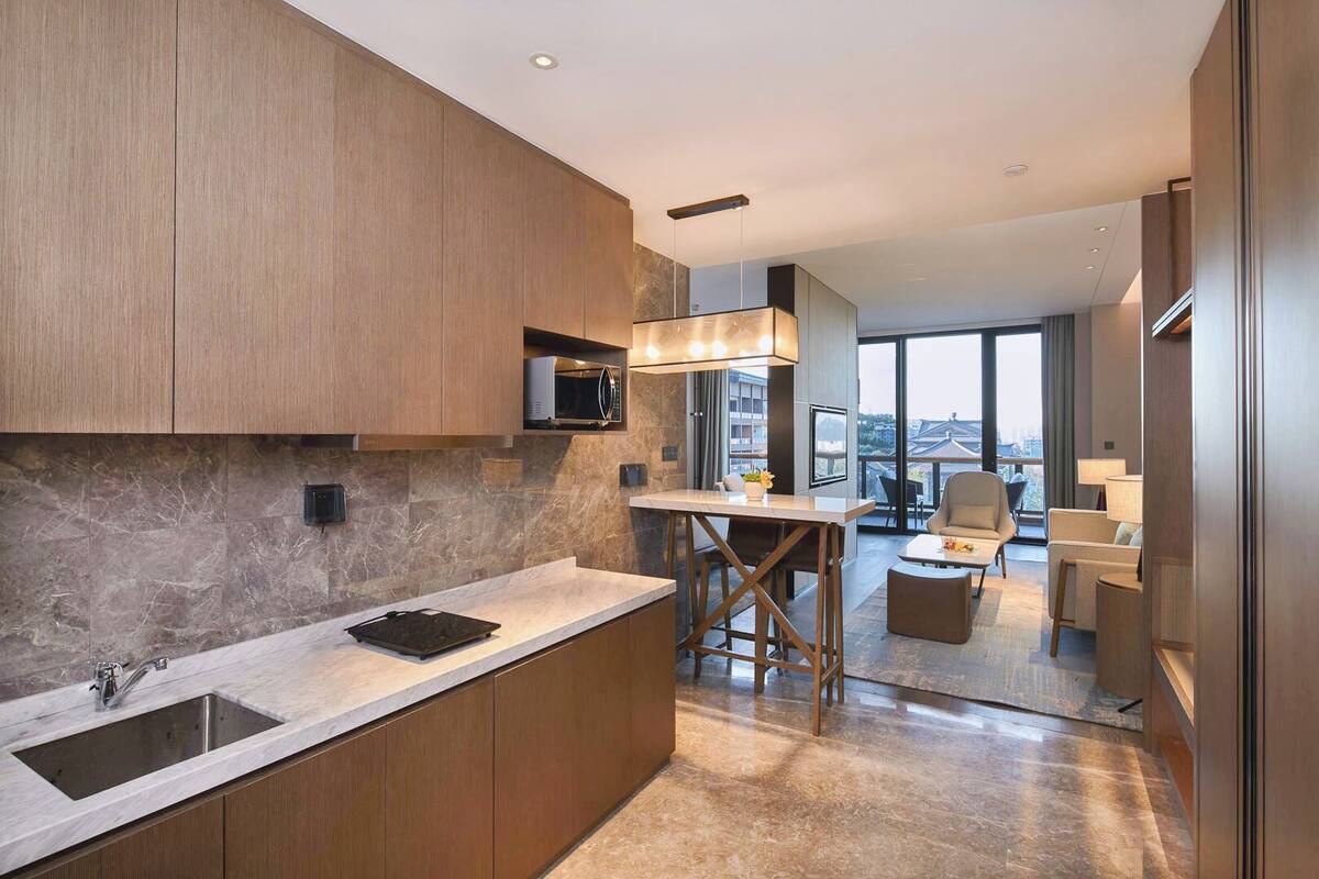 A modern kitchen with a marble countertop, wooden cabinets, and a built-in microwave.
