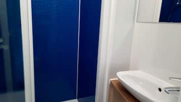 Un baño con lavamanos blanco, paredes azules y tocador de madera.