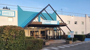 Een hotel met een blauw-witte gevel, een glazen entree en een bord met de tekst 'Kyrja Direct'.